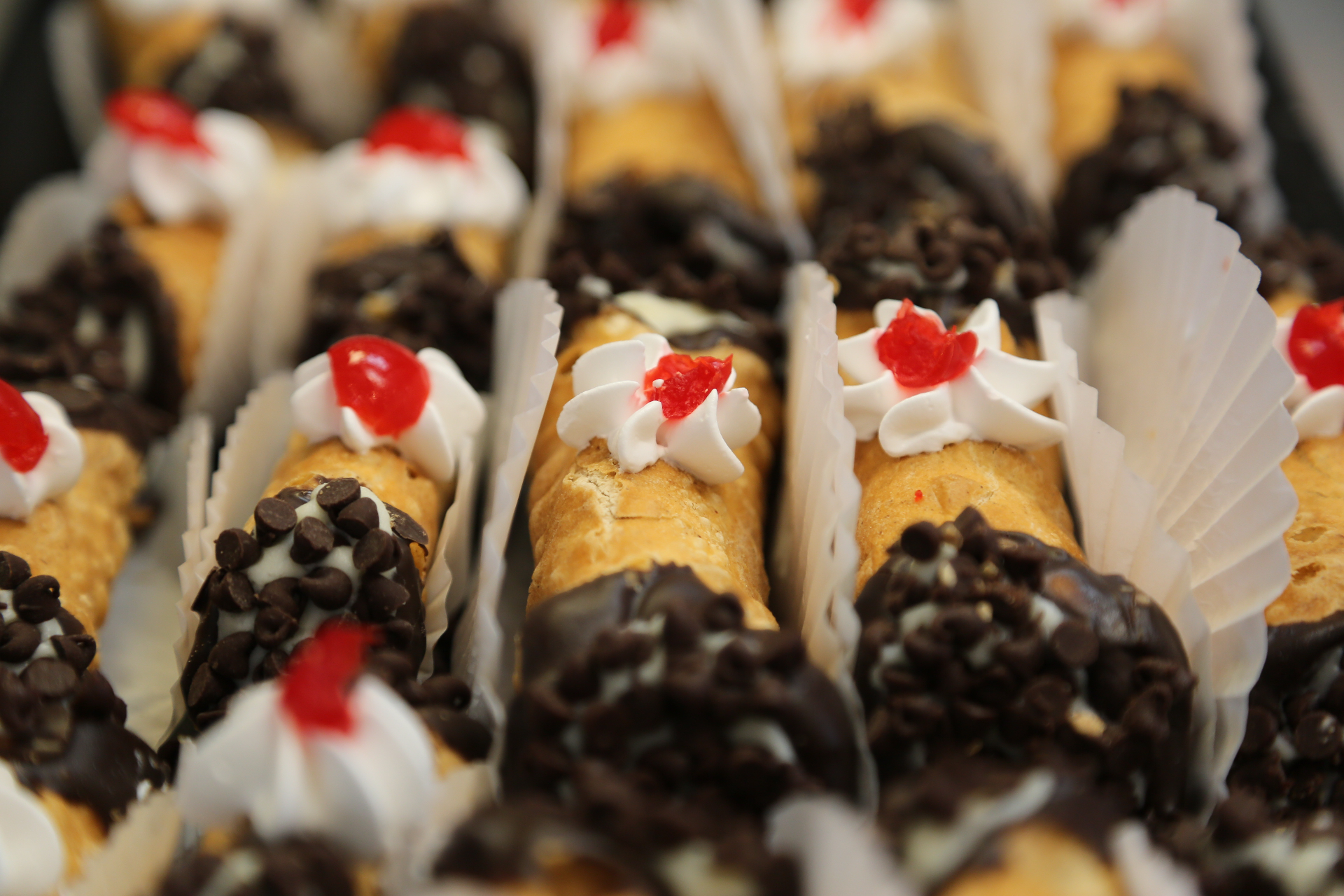 Tray of freshly filled cannoli with chocolate chips and cherries