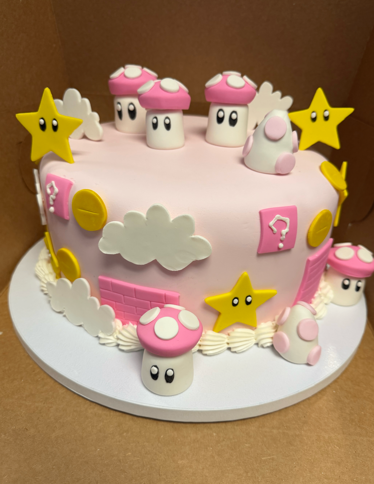 Pink fondant birthday cake with mushroom, star, and cloud toppers