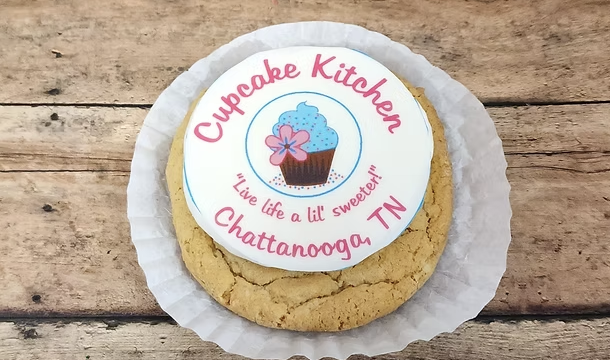 Vanilla iced sugar cookie with Cupcake Kitchen logo printed on the icing