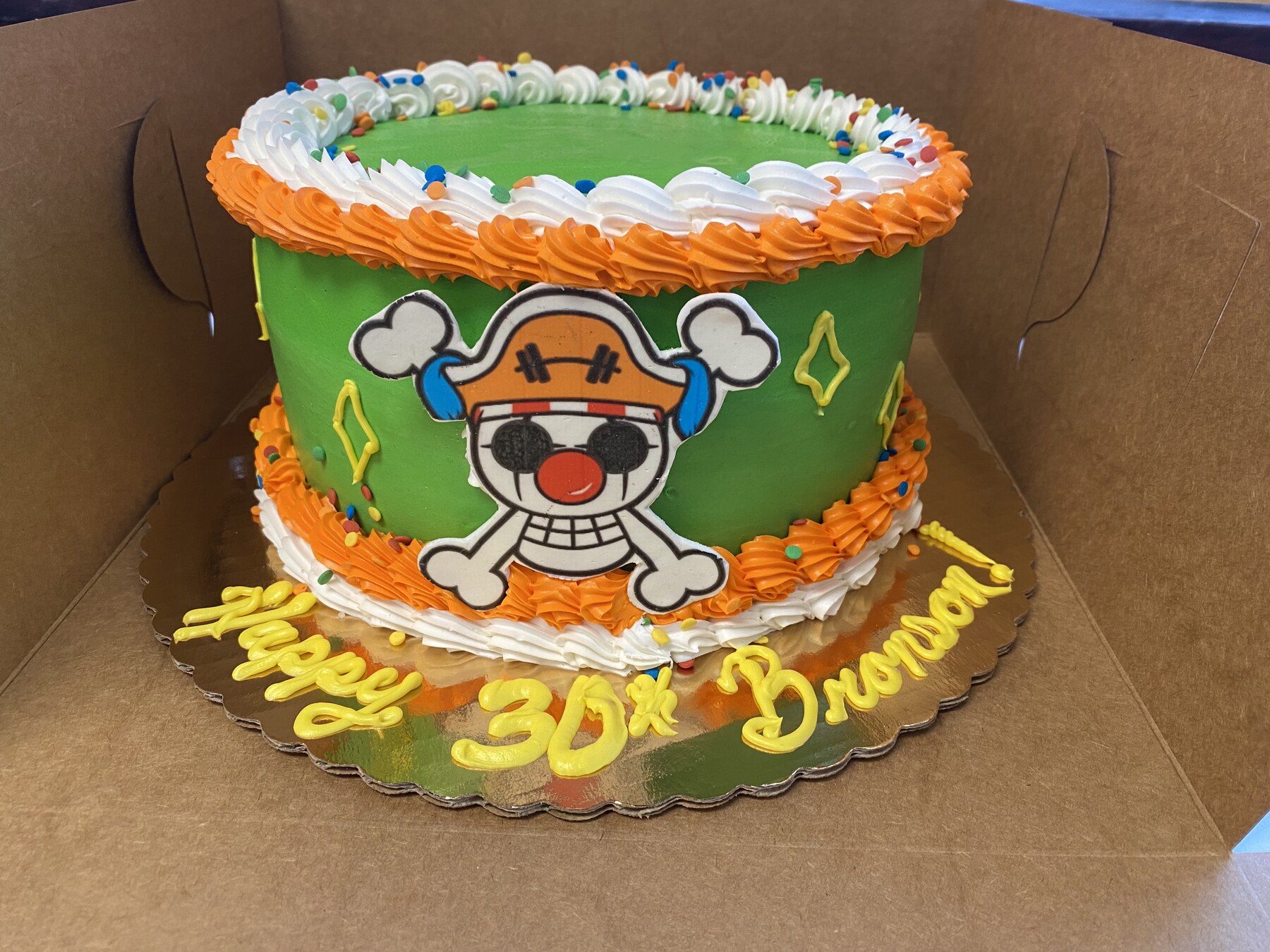 Green buttercream birthday cake with an anime-style character topper and sprinkles